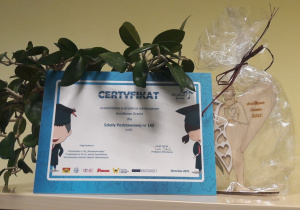 Certyfikat udziału w akcji "Aniołkowe Granie" Szkoły Podstawowej nr 142 w Łodzi oraz drewniany aniołek.i