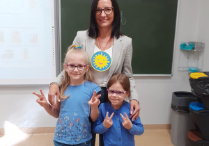 Zdjęcie przedstawia wychowawczynię klasy poierwszej z odznaczeniem na szyi w towarzystwie dwóch uczennic.