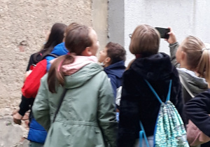Grupa dzieci przed budynkiem, na którym znajduje się mural