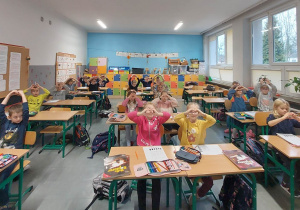 Uczniowie klasy pierwszej układają palce dłoni w serduszka.