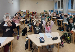 Uczniowie klasy trzeciej z dłońmi w górze i ułożonymi w kształt serca palcami.