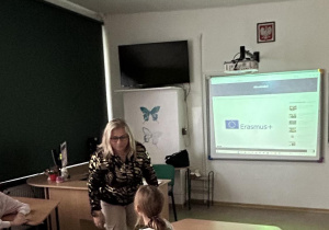 Koordynator projektu p. Justyna na tle tablicy interaktywnej z logo Erasmus+