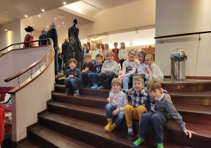 Pierwsza klasa siedząca na stopniach w holu teatru.