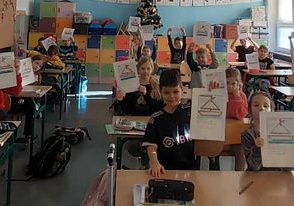 Uczniowie pokazujący prace przedstawiające łódki