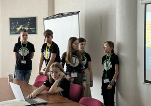 Nasi uczniowie na tle tablicy interaktywnej prezentują informacje o Polsce i Łodzi.