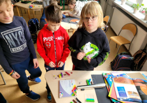 Chłopcy przy stoliku na którym na którym leży plastelina, papier wycinankowy, książki o kosmosie.