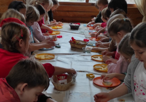 Uczniowie klas pierwszych wykrawające ciasteczka w różnych kształtach.