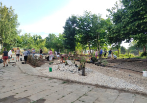 Uczniowie z rodzicami i nauczyciele przy pracy nad utworzeniem szkolnego ogrodu dydaktycznego.