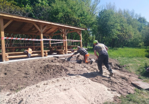 Prace wykończeniowe altany, panowie układający schodki z płyt chodnikowych.