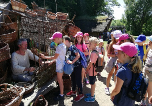 Na zdjęciu grupa dzieci pzyglądająca się pracy wikliniarza.