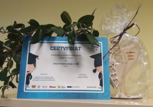 Certyfikat udziału w akcji "Aniołkowe Granie" Szkoły Podstawowej nr 142 w Łodzi oraz drewniany aniołek.i