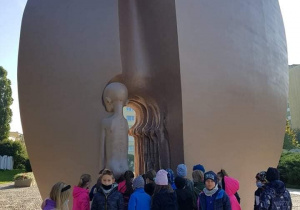 Na zdjęciu pomnik Pękniętego Serca, pod którym grupa dzieci składa laurki.