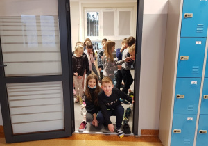 Dwoje dzieci w drzwiach sali lekcyjnej, których buty jako pierwsze przekroczyły próg. W tle widać pozostałych uczniów klasy drugiej.
