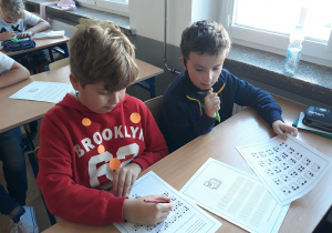 Dwóch chłopców odczytujących wiadomość zapisaną alfabetem Breila