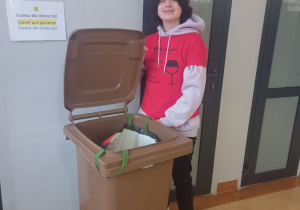 Uczennica klasy 8b z dużym kubłem na śmieci, w którym znajdują się jej podręczniki.