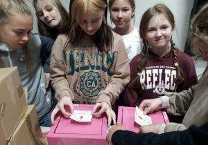 Na zdjęciu uczniowie klasy 7b oklejający różowe skrzyneczki logiem akcji.