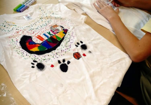 Na zdjęciu jedna z wykonanych koszulek i jeden z uczniów pracujący nad swoim projektem.