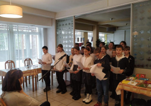Uczniowie z naszej szkoły, w strojach galowych, śpiewający kolędy dla pensjonariuszy Domu Opieki Społecznej.