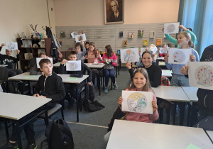 Uczniowie klasy szóstej pokazujący pokolorowane swoje prace z wilkami.