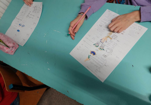 Na zdjęciu dłonie dzieci i karta pracy którą wypełniają uczniowie