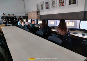 Uczennice siedzące przed komputerami, pracujące w programie graficznym.