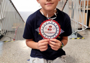 Chłopiec z klasy 1a prezentujący medal "Super chłopaka"