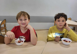 Dwaj chłopcy jedzący sałatkę owocową.