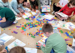 Dzieci z klasy 1a układające różne wzory na planszach.