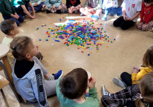 Dzieci siedzące w kręgu wokół wysypanych kolorowych klocków Numicon.