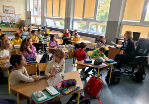 Nauczycielka języka polskiego czytająca uczniom klasy 1a książkę "Cukierku ty łobuzie".