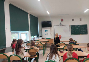 Nauczycielka języka polskiego prezentująca uczniom książkę, którą będzie im czytać.