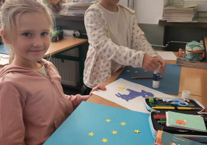 Dziewczynki przy pracy tworzące własne gwiazdozbiory z naklejanych żółtych gwiazdek na niebieski karton.