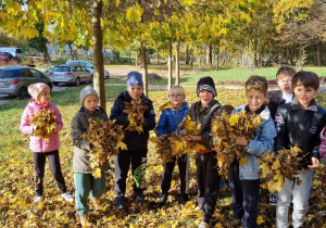 Grupa dzieci z liśćmi w rękach.