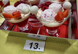 Piękne biało-czerwone desery w pucharkach udekorowane owocami i słodkościami.