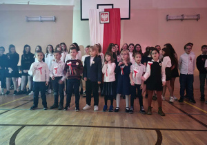 Uczniowie klasy pierwszej a śpiewający piosenkę patriotyczną.