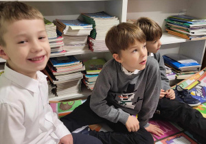 Dzieci siedzące w bibliotece na kolorowej macie.
