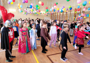 Dzieci w kolorowych strojach tańczące na balu.