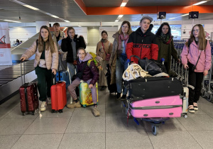Grupa uczniów na lotnisku z bagażami.