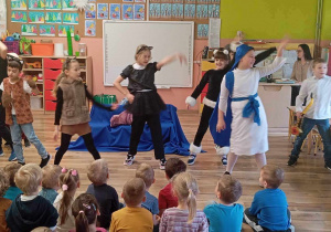 Tańczący aktorzy, występujący przed małą przedszkolną publicznością.