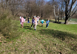 Dzieci rozproszone w szkolnym ogrodzie biegnące w poszukiwaniu czekoladowych jajek.