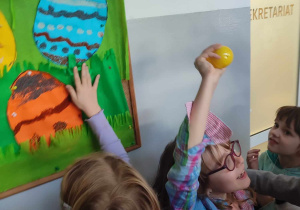 Dzieci przy tablicy z ich pracami, jedna z dziewczynek znalazła kolejną wskazówkę z escape roomu.