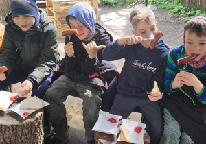 Na zdjęciu chłopcy z klasy 1a jedzący kiełbaski z ogniska.