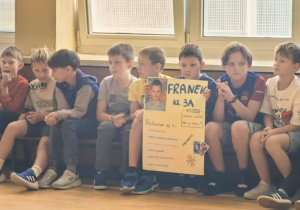 Chłopcy z klasy 3a, wśród nich kandydat do samorządu uczniowskiego klas 1-3 prezentujący plakat wyborczy.