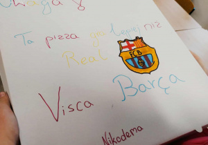Pudełko z pizzą wykonane specjalnie dla kolegi. Na nim napis: Uwaga! Ta pizza gra lepiej niż Real, Pizza Nikodema.