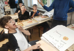 Chłopcy konsumujący pizzę.