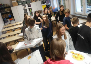 Dziewczęta z klasy siódmej wręczające kolegom pizze w spersonalizowanych pudełkach.