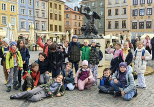 Klasa trzecia pozując do zdjęci przed pomnikiem Warszawskiej Syrenki.