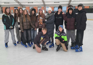 Uczniowie klasy siódmej pozujący do wspólnego zdjęcia na tafli lodowiska.