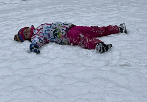 Dziewczynka leżąca na śniegu.