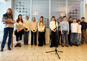 Uczniowie wraz z opiekunem śpiewający kolędy.